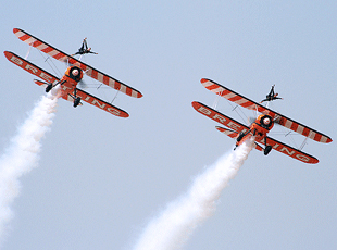 Wingwalkers demonstrating their acrobatic skills in midair